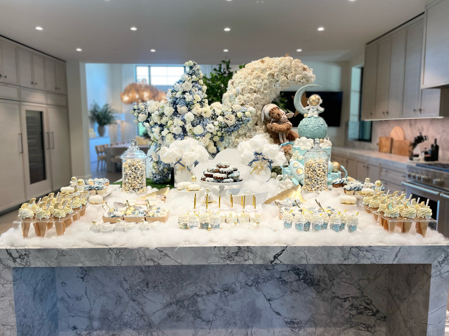 Decorative dessert table with flowers and pastries in a modern kitchen.