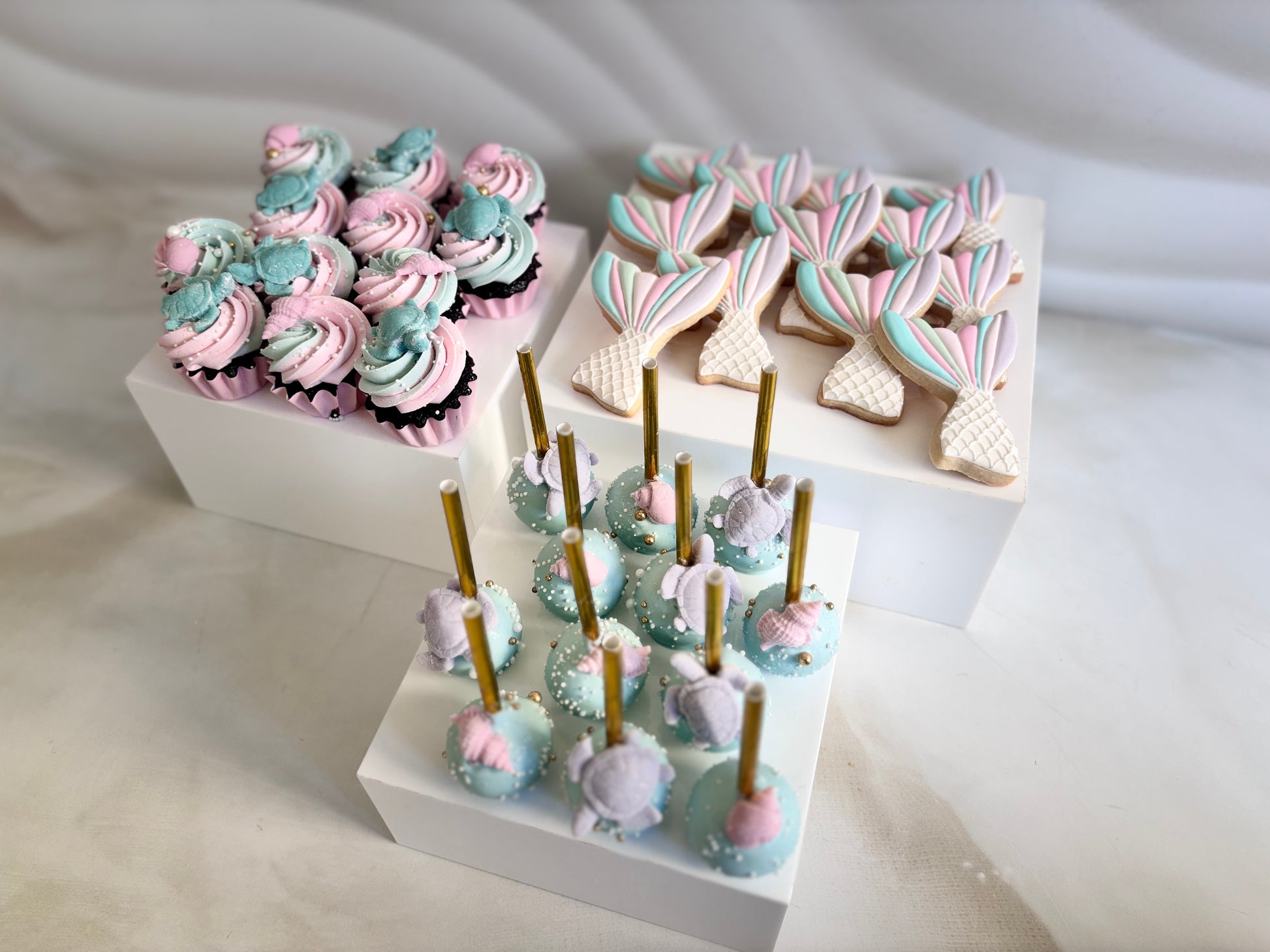 Decorative cookies and cake pops on a white surface