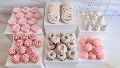 Assorted desserts including cookies, cupcakes, and macarons on a white surface.