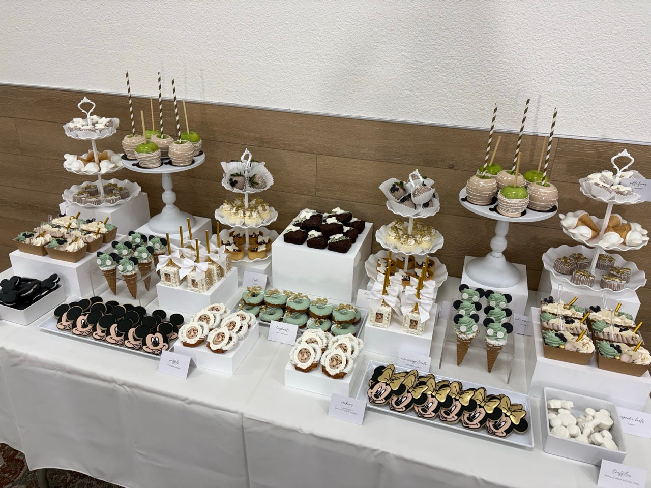 Dessert table with various pastries and treats on tiered stands.